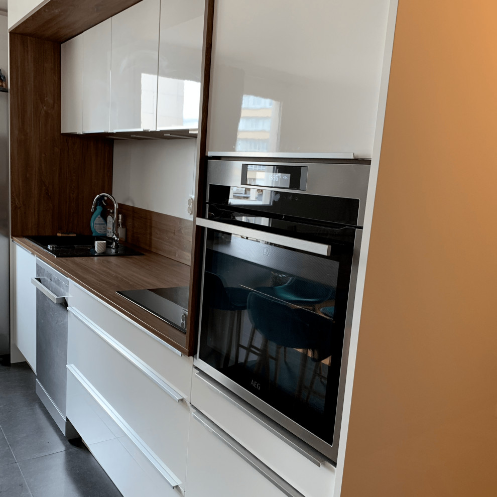 Foto på ett mellanstort vintage brun linjärt kök med öppen planlösning, med en undermonterad diskho, träbänkskiva, brunt stänkskydd, stänkskydd i trä, integrerade vitvaror, skiffergolv, en köksö och grått golv