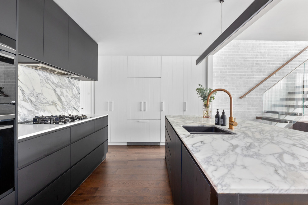 This is an example of a mid-sized contemporary l-shaped open plan kitchen in Melbourne with a double-bowl sink, black cabinets, marble benchtops, marble splashback, black appliances, medium hardwood floors and with island.