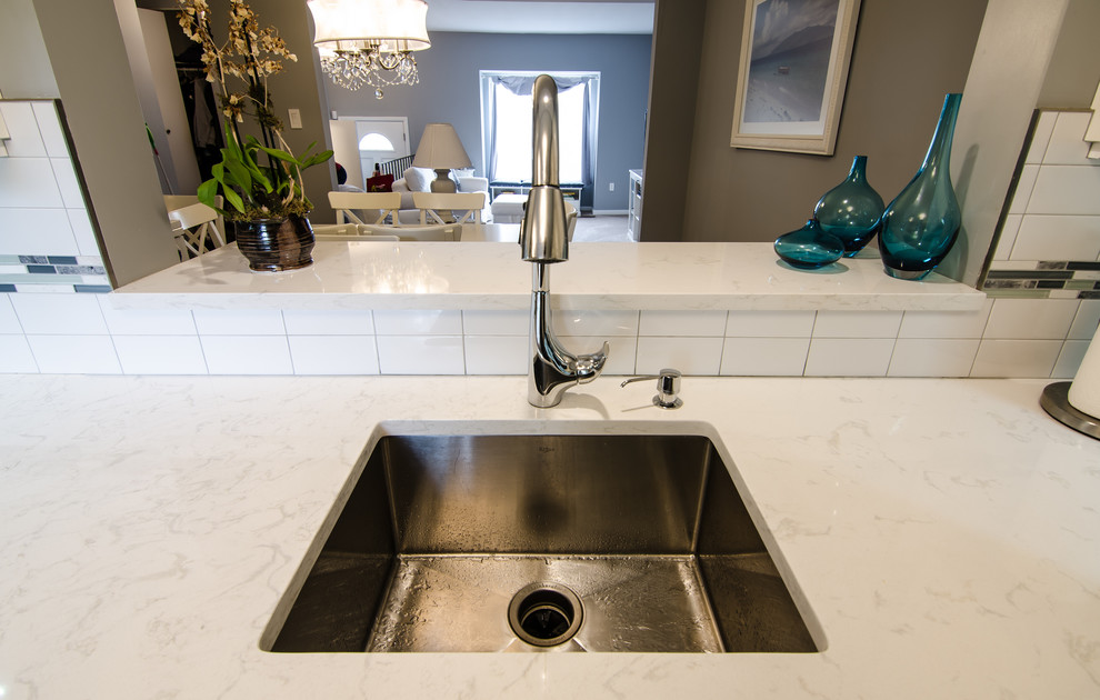 Enclosed kitchen - mid-sized transitional l-shaped vinyl floor enclosed kitchen idea in DC Metro with an undermount sink, shaker cabinets, quartz countertops, white backsplash, ceramic backsplash, black appliances and no island