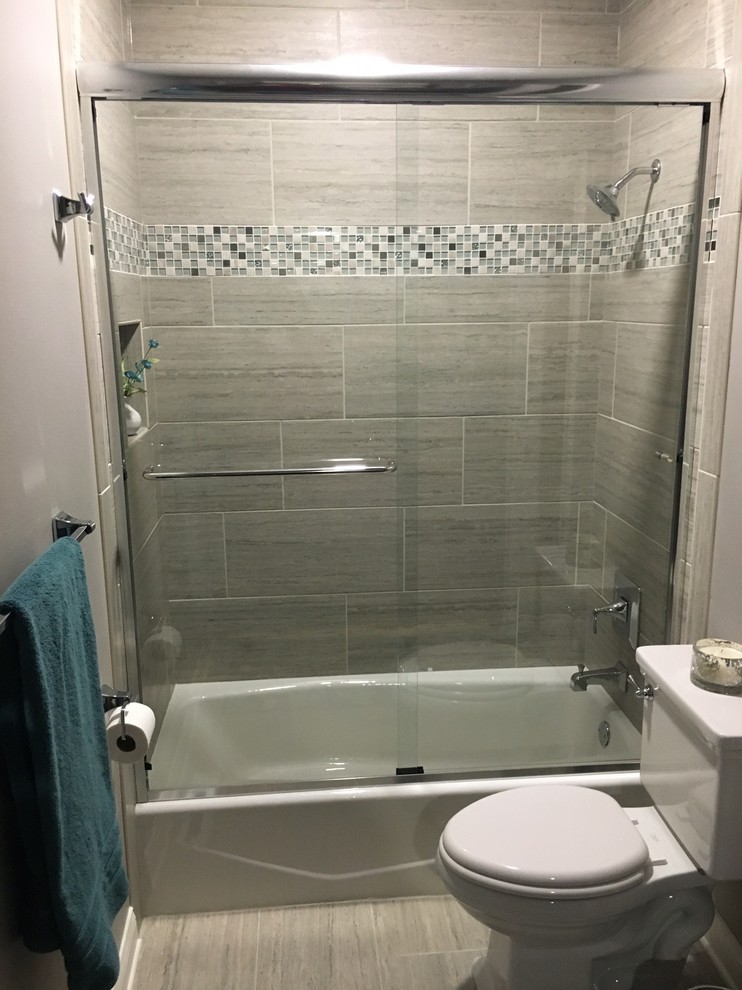 Design ideas for a small transitional 3/4 bathroom in Milwaukee with shaker cabinets, grey cabinets, an alcove tub, a shower/bathtub combo, a two-piece toilet, gray tile, porcelain tile, grey walls, porcelain floors, an undermount sink and solid surface benchtops.