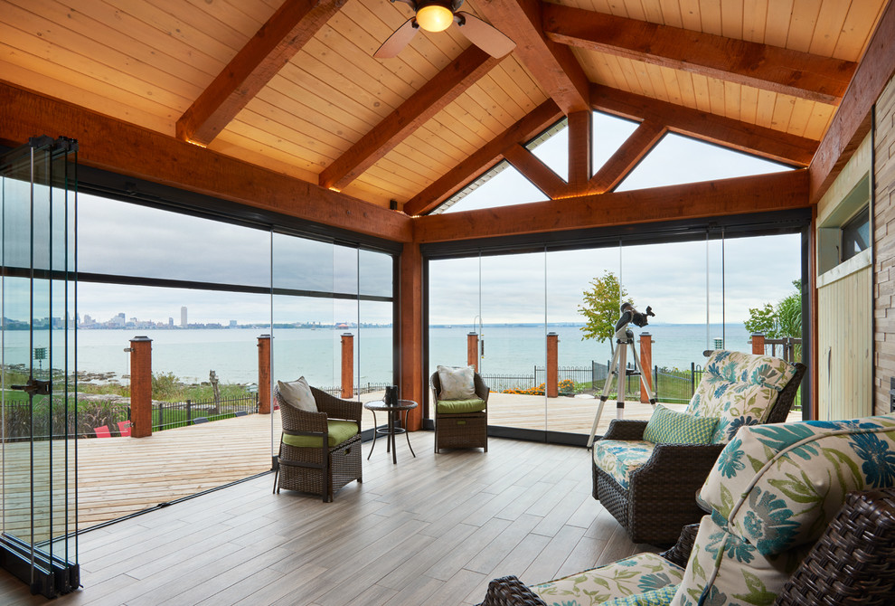 Large contemporary sunroom in Toronto with porcelain floors, a standard fireplace and a wood fireplace surround.