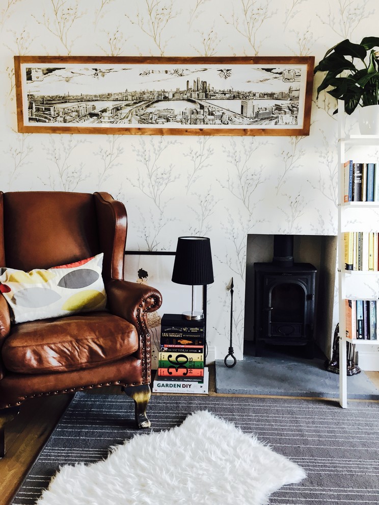 Photo of a small traditional open concept living room in Hampshire with a library, grey walls, light hardwood floors, a wood stove, a concrete fireplace surround and no tv.