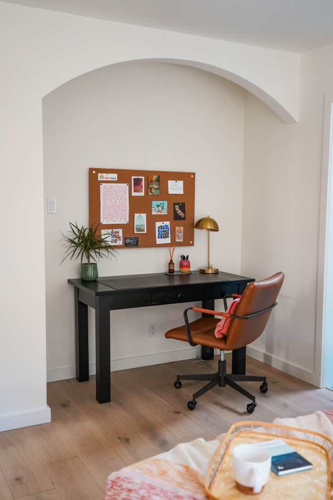 Photo of a large beach style home office in San Francisco with white walls and light hardwood floors.