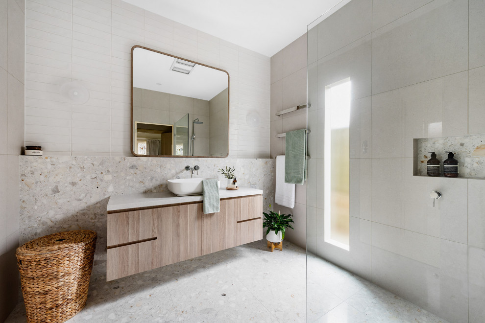 Idéer för att renovera ett mellanstort funkis vit vitt en-suite badrum, med släta luckor, skåp i ljust trä, en öppen dusch, en vägghängd toalettstol, grå kakel, tunnelbanekakel, grå väggar, cementgolv, ett fristående handfat, bänkskiva i kalksten, grått golv och med dusch som är öppen