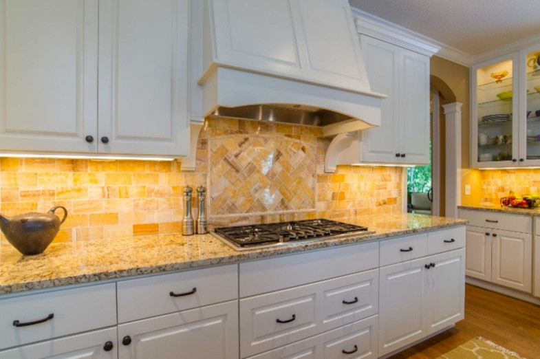 Inspiration for a transitional single-wall medium tone wood floor open concept kitchen remodel in Minneapolis with a double-bowl sink, recessed-panel cabinets, white cabinets, granite countertops, gray backsplash, stainless steel appliances and an island