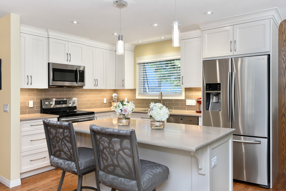Example of a mid-sized transitional l-shaped medium tone wood floor and beige floor eat-in kitchen design in Calgary with an undermount sink, recessed-panel cabinets, white cabinets, quartz countertops, gray backsplash, glass tile backsplash, stainless steel appliances and an island