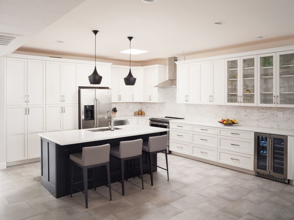 Example of a transitional l-shaped porcelain tile and beige floor open concept kitchen design in Phoenix with an undermount sink, shaker cabinets, white cabinets, quartz countertops, gray backsplash, marble backsplash, stainless steel appliances, an island and white countertops