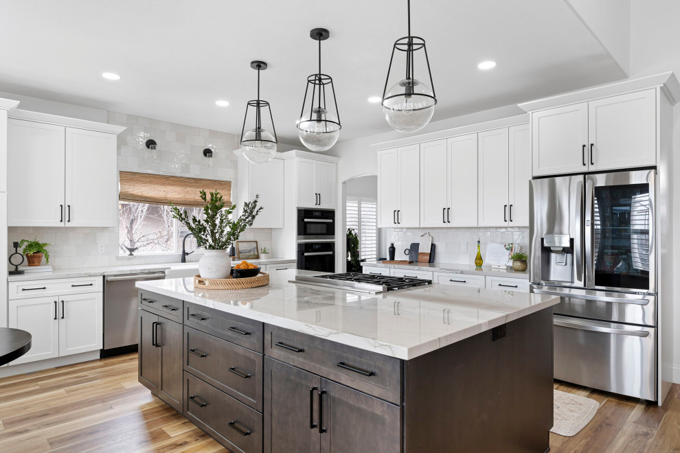 Transitional vinyl floor and brown floor kitchen photo with a farmhouse sink, shaker cabinets, white cabinets, quartzite countertops, white backsplash and stainless steel appliances