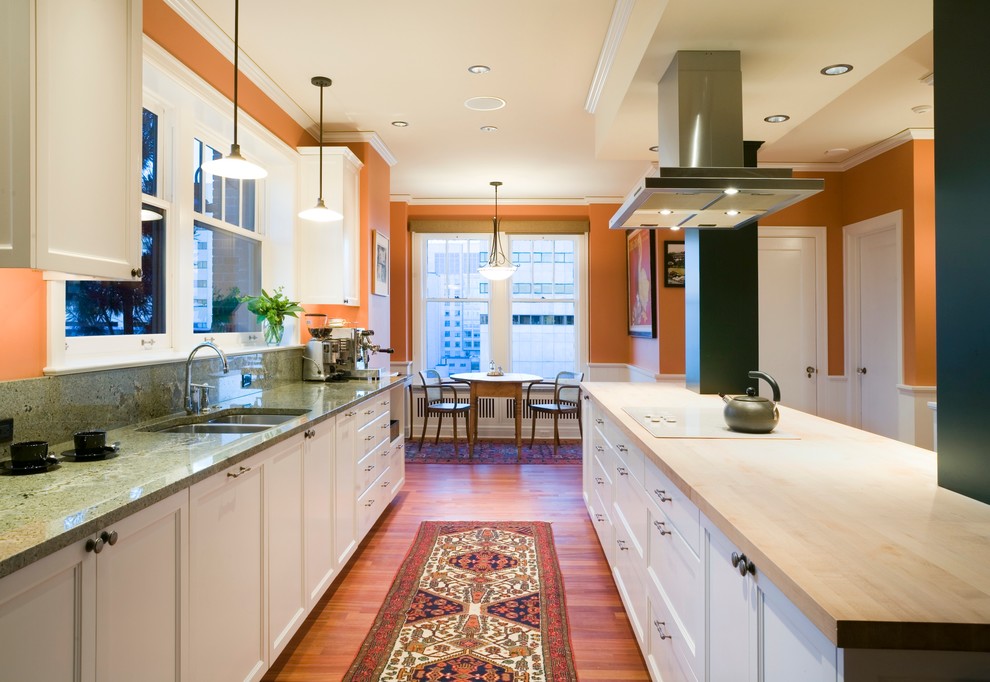 This is an example of a traditional eat-in kitchen in Seattle with a double-bowl sink, recessed-panel cabinets, white cabinets and wood benchtops.