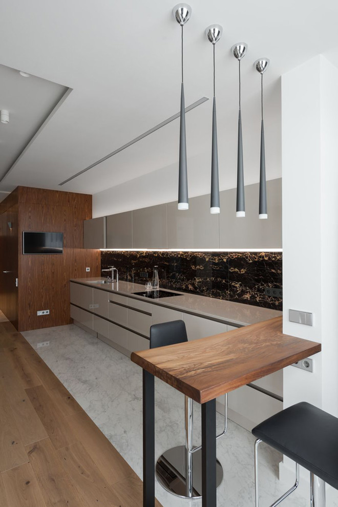 This is an example of a contemporary single-wall kitchen in Moscow with flat-panel cabinets, beige cabinets, black splashback, marble floors, a peninsula, white floor and beige benchtop.