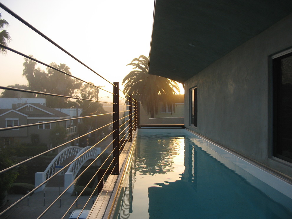 This is an example of a small modern rooftop rectangular lap pool in Los Angeles with a water feature and decking.