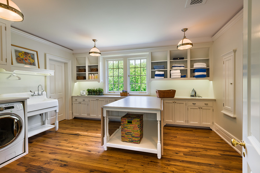 Photo of a large traditional l-shaped dedicated laundry room in Philadelphia with a farmhouse sink, white cabinets, shaker cabinets, wood benchtops, white walls, light hardwood floors, a side-by-side washer and dryer, brown floor and beige benchtop.