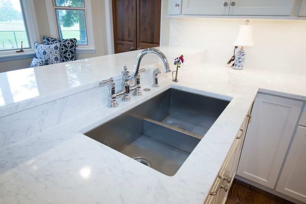 Inspiration for a huge transitional medium tone wood floor open concept kitchen remodel with an undermount sink, shaker cabinets, white cabinets, marble countertops, white backsplash, ceramic backsplash, stainless steel appliances and two islands
