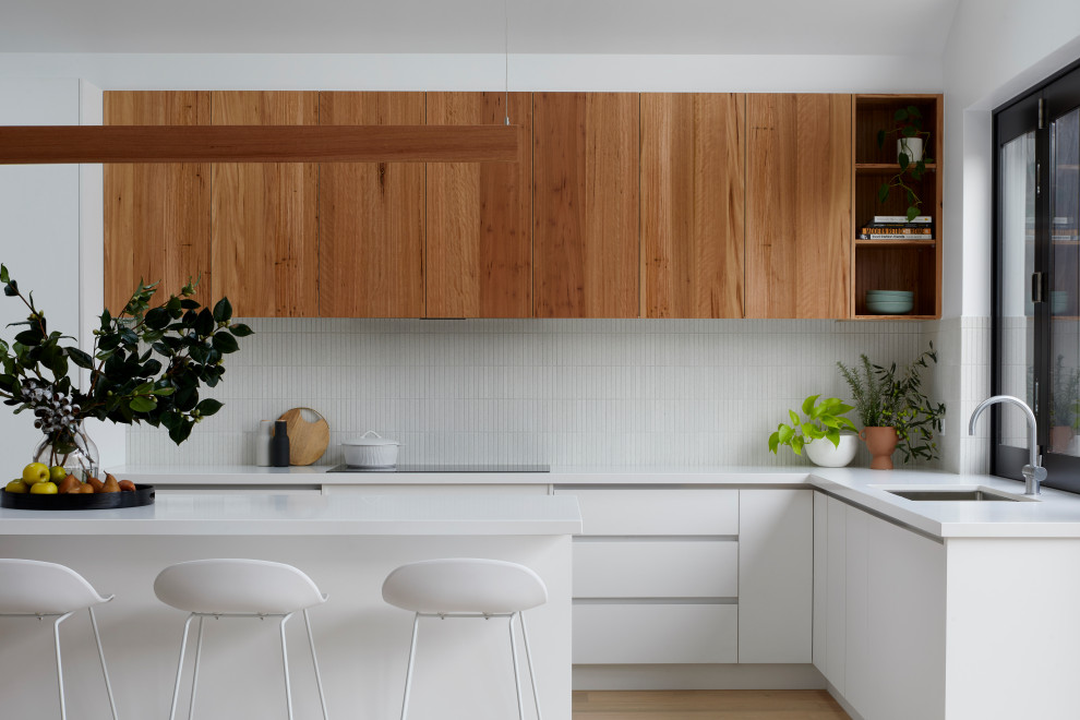 Example of a mid-sized trendy l-shaped medium tone wood floor and vaulted ceiling kitchen pantry design in Melbourne with a double-bowl sink, quartz countertops, white backsplash, subway tile backsplash, an island and white countertops