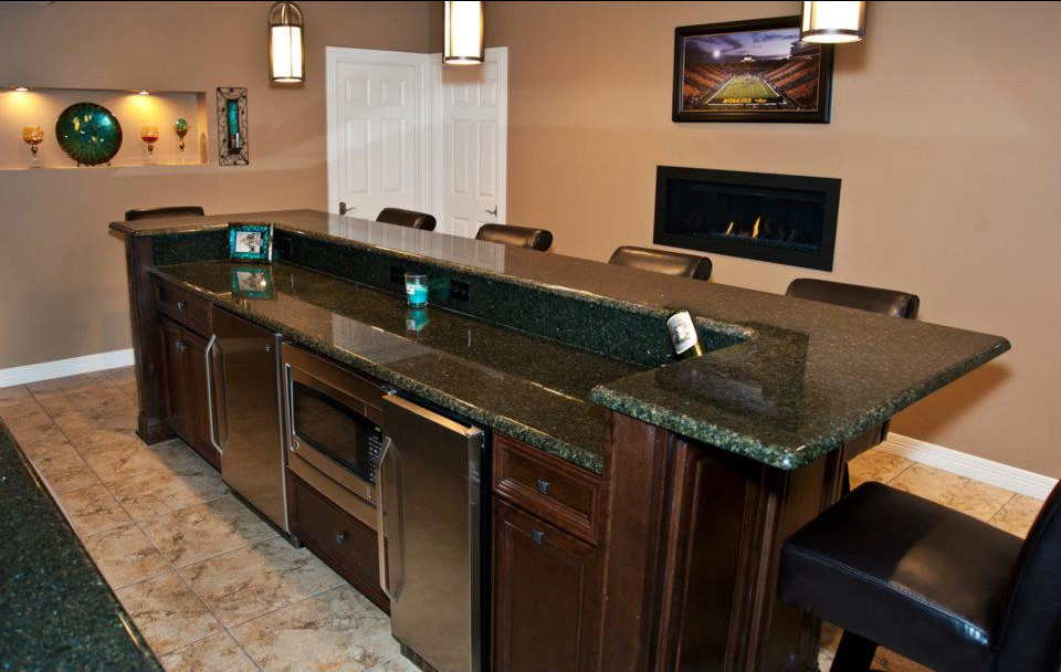 This is an example of a mid-sized traditional galley seated home bar in Omaha with an undermount sink, recessed-panel cabinets, dark wood cabinets, marble benchtops and ceramic floors.