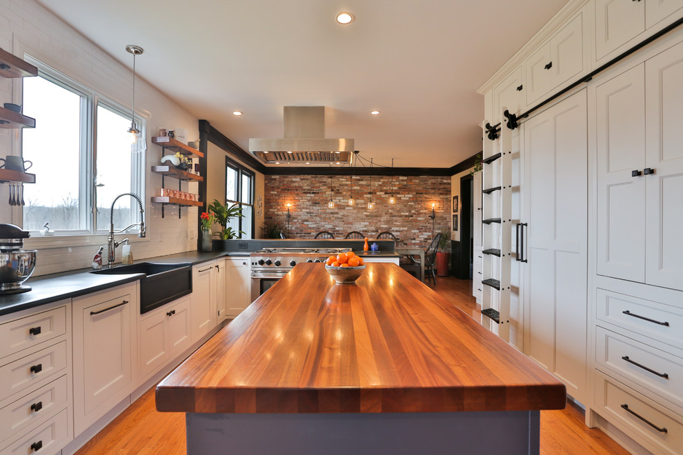 Design ideas for a large country u-shaped eat-in kitchen in New York with a farmhouse sink, white cabinets, wood benchtops, white splashback, medium hardwood floors, with island, brown floor, brown benchtop, recessed-panel cabinets, subway tile splashback and stainless steel appliances.