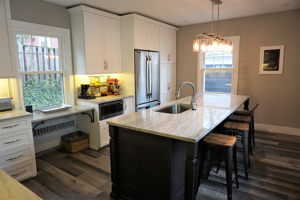Example of a mid-sized transitional laminate floor and gray floor eat-in kitchen design with raised-panel cabinets, white cabinets, granite countertops, gray backsplash, ceramic backsplash, stainless steel appliances, an island, gray countertops and a drop-in sink