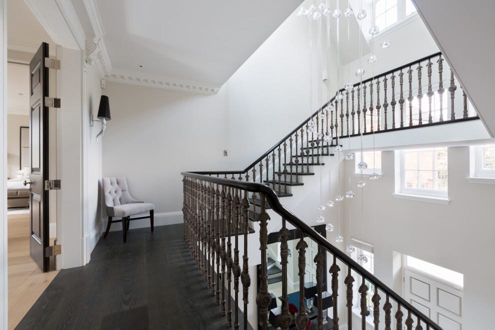 This is an example of a large contemporary metal u-shaped staircase in London with wood risers and metal railing.