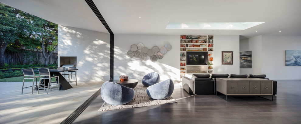 This is an example of a large modern grey and white open plan living room in Dallas with white walls, dark hardwood flooring, a standard fireplace, a metal fireplace surround, a built-in media unit and grey floors.