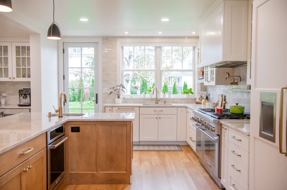 Mid-sized transitional u-shaped kitchen in Other with a double-bowl sink, shaker cabinets, white cabinets, quartzite benchtops, white splashback, subway tile splashback, stainless steel appliances, laminate floors, with island and white benchtop.