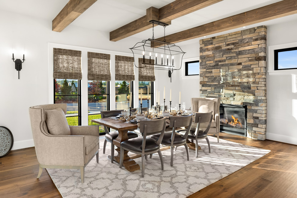 Inspiration for a large country separate dining room in Portland with white walls, medium hardwood floors, a standard fireplace, a stone fireplace surround and brown floor.