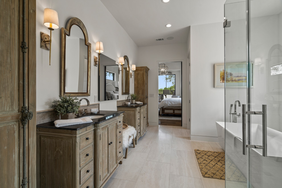Design ideas for a country bathroom in Austin with shaker cabinets, medium wood cabinets, a freestanding tub, white walls, an undermount sink, grey floor, black benchtops, a double vanity and a freestanding vanity.