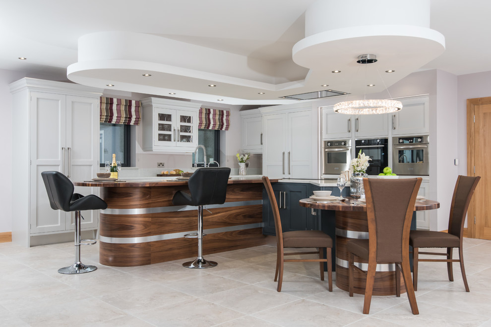 Design ideas for a large transitional l-shaped eat-in kitchen in Other with shaker cabinets, white cabinets, an integrated sink, quartzite benchtops, stainless steel appliances, ceramic floors, multiple islands, white floor and black benchtop.