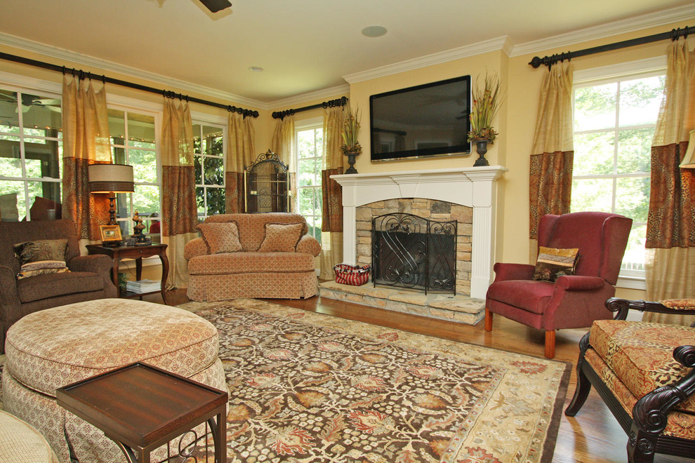 This is an example of a mid-sized traditional formal open concept living room in Atlanta with yellow walls, medium hardwood floors, a standard fireplace, a tile fireplace surround, no tv and brown floor.