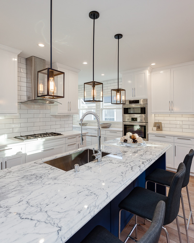 Design ideas for a large modern l-shaped open plan kitchen in Los Angeles with an undermount sink, shaker cabinets, white cabinets, marble benchtops, white splashback, subway tile splashback, stainless steel appliances, vinyl floors and with island.
