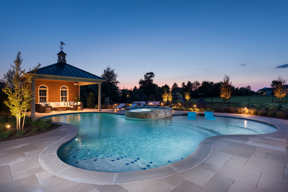 Cette image montre un grand piscine avec aménagement paysager arrière traditionnel sur mesure avec des pavés en pierre naturelle.
