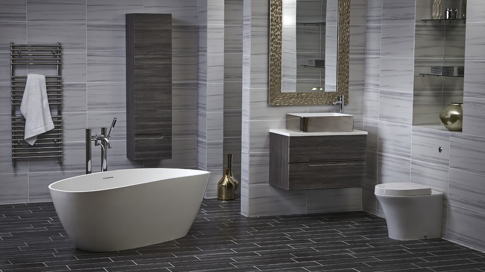 Design ideas for a large modern master bathroom in Hertfordshire with flat-panel cabinets, a freestanding tub, a one-piece toilet, gray tile and a vessel sink.