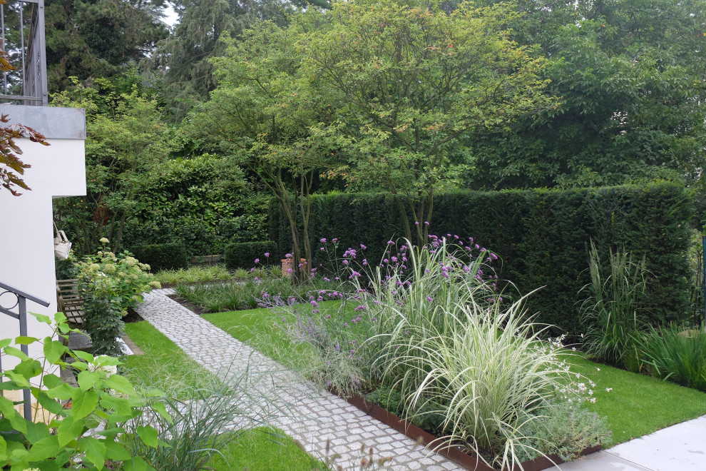 Geometrischer, Mittelgroßer, Halbschattiger Moderner Garten im Sommer, neben dem Haus mit Rasenkanten, Natursteinplatten und Metallzaun in Bonn