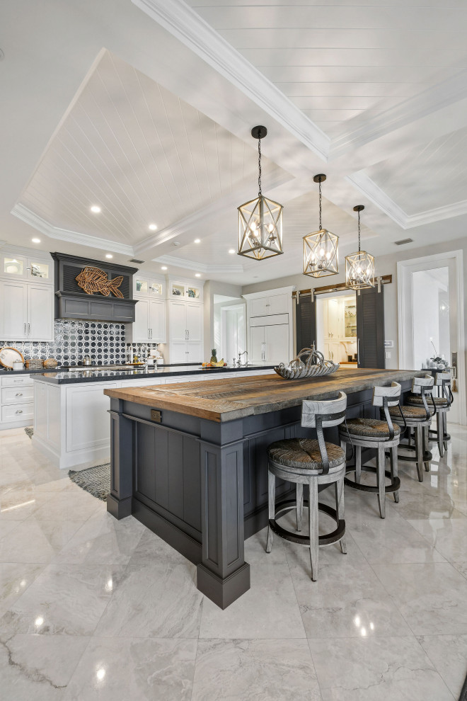Inspiration for a large transitional l-shaped kitchen pantry in Miami with an undermount sink, beaded inset cabinets, white cabinets, wood benchtops, blue splashback, marble splashback, panelled appliances, travertine floors, multiple islands, beige floor and brown benchtop.