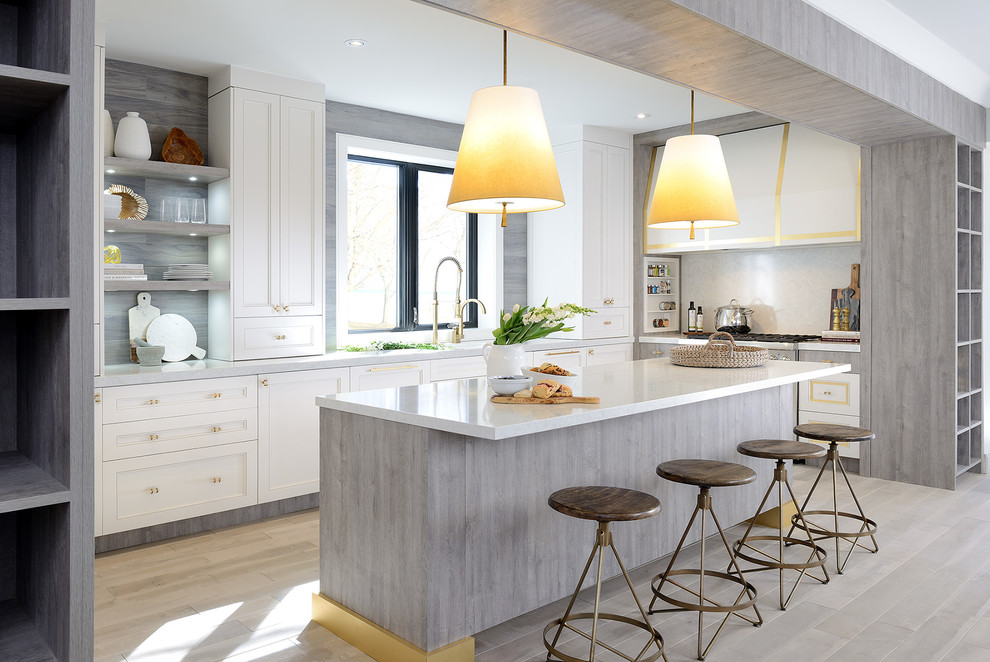 Mid-sized transitional u-shaped light wood floor and gray floor open concept kitchen photo in Toronto with an undermount sink, shaker cabinets, white cabinets, solid surface countertops, stainless steel appliances and an island