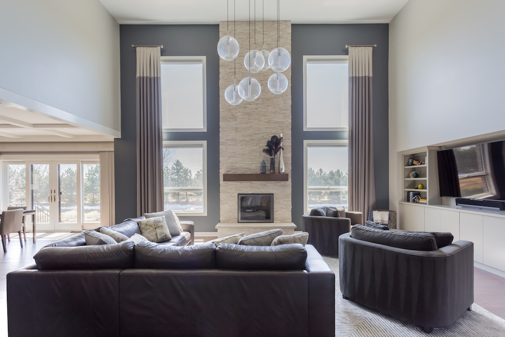 Inspiration for a large modern open concept family room in Chicago with grey walls, medium hardwood floors, a standard fireplace, a stone fireplace surround and a built-in media wall.