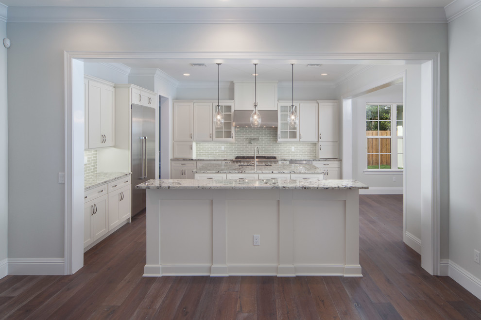 Inspiration for a large traditional kitchen in Orlando with a drop-in sink, glass-front cabinets, white cabinets, granite benchtops, grey splashback, subway tile splashback, stainless steel appliances, dark hardwood floors and multiple islands.