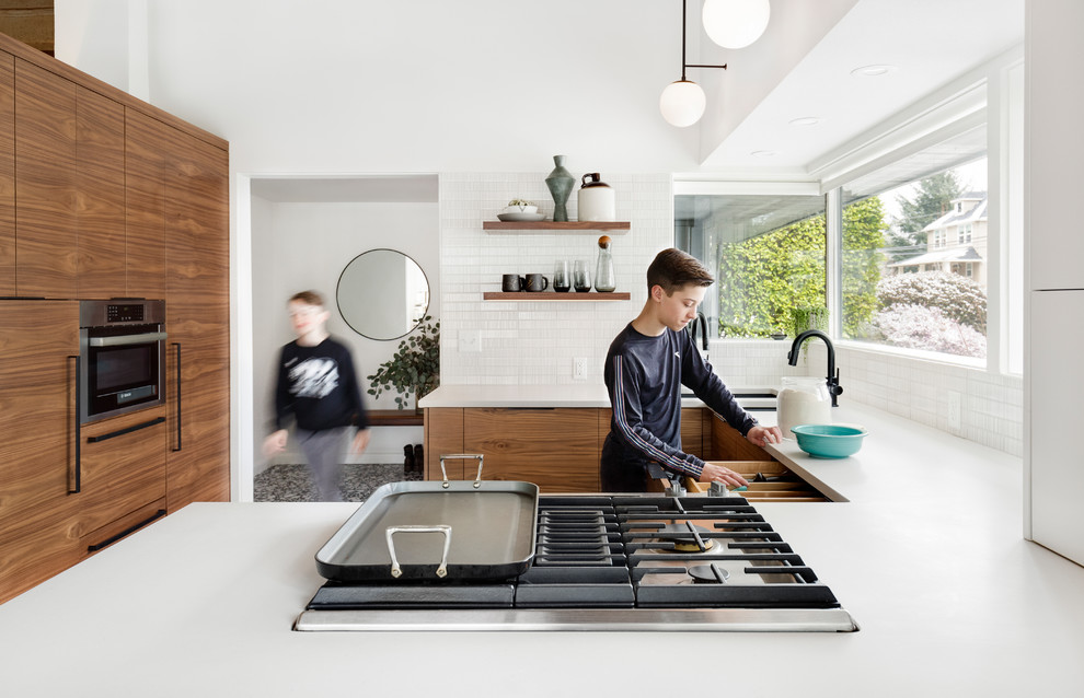 Photo of a small midcentury u-shaped eat-in kitchen in Portland with an undermount sink, flat-panel cabinets, dark wood cabinets, quartz benchtops, white splashback, ceramic splashback, panelled appliances, terrazzo floors, black floor and white benchtop.