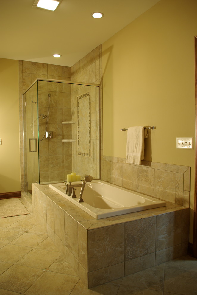 Mid-sized traditional master bathroom in Milwaukee with recessed-panel cabinets, medium wood cabinets, a drop-in tub, a corner shower, a one-piece toilet, yellow walls, porcelain tile, travertine floors and tile benchtops.