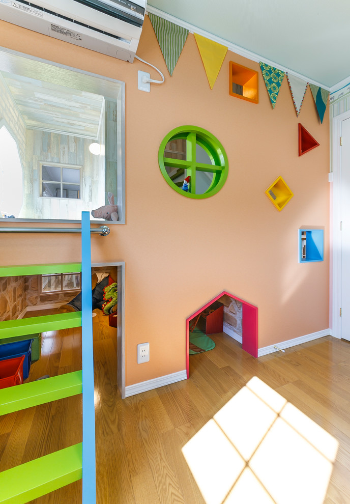 Photo of a contemporary gender-neutral kids' room in Other with orange walls and light hardwood floors.