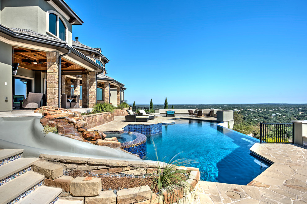 Water slide - large mediterranean backyard custom-shaped and stone infinity water slide idea in Austin