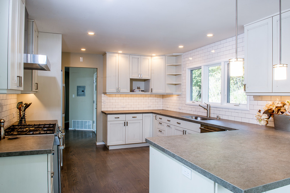 Photo of a large transitional u-shaped separate kitchen in San Francisco with an undermount sink, shaker cabinets, white cabinets, zinc benchtops, white splashback, subway tile splashback, stainless steel appliances, dark hardwood floors, a peninsula and brown floor.
