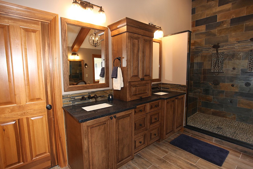 Large mountain style master slate tile brown floor freestanding bathtub photo in Indianapolis with brown cabinets, beige walls and an undermount sink