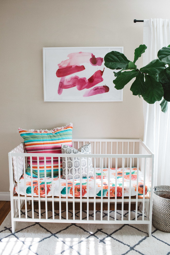 Design ideas for a mid-sized eclectic nursery for girls in Orange County with beige walls and medium hardwood floors.