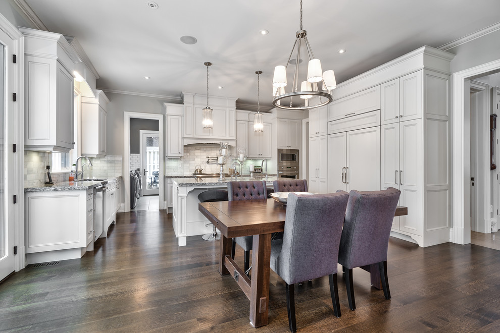 Large transitional u-shaped dark wood floor and brown floor open concept kitchen photo in Toronto with an undermount sink, beaded inset cabinets, white cabinets, granite countertops, gray backsplash, marble backsplash, paneled appliances, an island and multicolored countertops