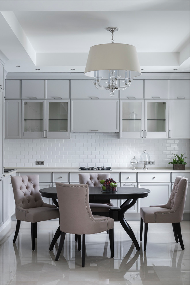 Photo of a transitional eat-in kitchen in Moscow with white splashback, subway tile splashback, no island, glass-front cabinets and grey cabinets.