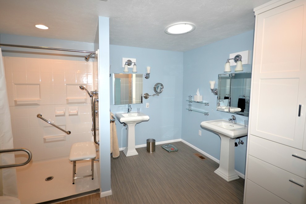 This is an example of a mid-sized traditional master bathroom in Boise with shaker cabinets, white cabinets, a curbless shower, a two-piece toilet, blue walls, vinyl floors, a pedestal sink, an alcove tub, ceramic tile, solid surface benchtops, beige floor, a shower curtain and white benchtops.