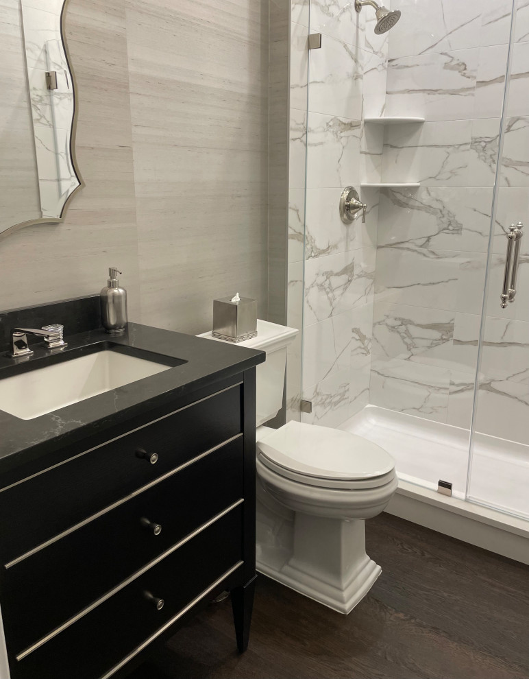 Inspiration for a mid-sized transitional 3/4 bathroom in New York with flat-panel cabinets, black cabinets, an alcove shower, a two-piece toilet, white tile, porcelain tile, medium hardwood floors, an undermount sink, engineered quartz benchtops, brown floor, a sliding shower screen, black benchtops, a single vanity, a freestanding vanity and wallpaper.
