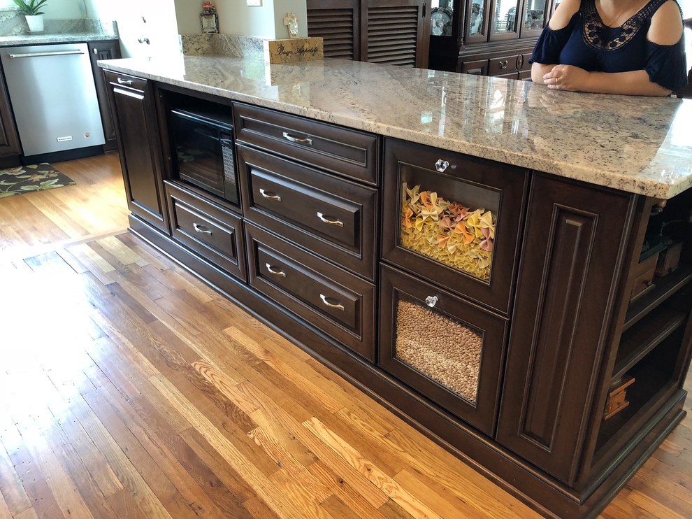 Mid-sized elegant l-shaped light wood floor and brown floor eat-in kitchen photo with an undermount sink, raised-panel cabinets, dark wood cabinets, granite countertops, multicolored backsplash, ceramic backsplash, stainless steel appliances, an island and multicolored countertops