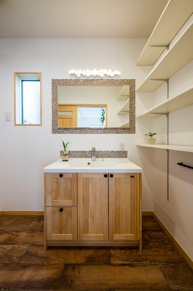 Photo of an asian powder room in Other with mosaic tile, porcelain floors, a wall-mount sink, brown floor, recessed-panel cabinets, medium wood cabinets and white walls.