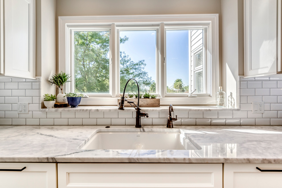Example of a transitional open concept kitchen design in Chicago with white backsplash, subway tile backsplash, two islands and a drop-in sink